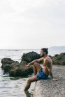 Человек, сидящий на берегу моря — стоковое фото