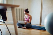 Mulher usando laptop em roupas de exercício — Fotografia de Stock
