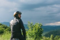 Jeune motard homme à moto regardant par-dessus son épaule, Florence, Toscane, Italie — Photo de stock