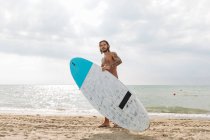 Surfer with surfboard by seaside — Stock Photo