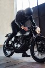 Junger männlicher Motorradfahrer rammt Oldtimer-Motorrad in Garage — Stockfoto