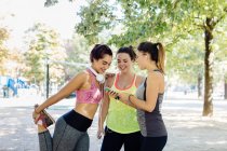 Friends exercising and using cellphone in park, close-up view — Stock Photo