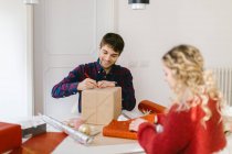 Couple wrapping Christmas gifts at home — Stock Photo