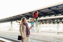 Woman with heart shaped balloon at train station, Firenze, Toscana, Italy — Stock Photo