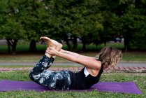Mujer rubia madura haciendo yoga en un parque. - foto de stock