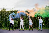 Змішана гоночна група друзів, які висіли разом у місті, використовуючи барвисті димові бомби . — стокове фото