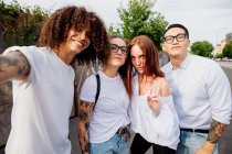 Mixed race group of friends hanging out together in town, taking selfie with mobile phone. — Stock Photo