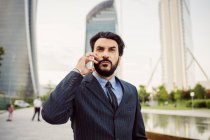 Portrait of bearded businessman wearing dark suit, using mobile phone. — Stock Photo