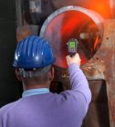 Чоловік працює на металургійному заводі, оглядаючи сталеву трубку . — стокове фото
