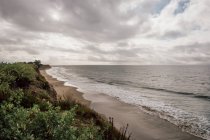Vista ao longo da praia arenosa sob um céu nublado perto de Santa Barbara, Califórnia, EUA. — Fotografia de Stock