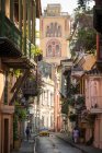 View along narrow street in the Old City, elegant historic houses with balconies and tall church tower — Stock Photo