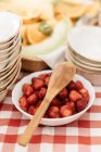High angle close up of wooden spoon on bowl of strawberries. — Stock Photo
