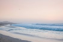Волны разбиваются о берег белого песка — стоковое фото