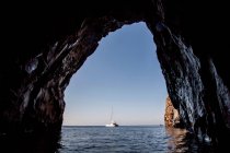 Sailboat viewed from cave in ocean — Stock Photo