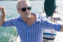 Portrait of man on yacht wearing checked shirt and sunglasses — Stock Photo