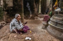 Монахиня-преданная, зажигание благовоний и молитва в храме Преах-хан, Ангкор, Камбоджа — стоковое фото