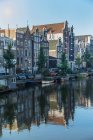 Building exteriors reflected in canal, Amsterdam, Netherlands — Stock Photo
