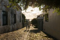 Dos personas paseando por la calle adoquinada, Barrio Histórico, Colonia del Sacramento, Colonia, Uruguay - foto de stock