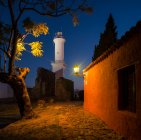 View of lighthouse at night from cobbled street, Barrio Historico (Old Quarter), Colonia del Sacramento, Colonia, Uruguay — Stock Photo