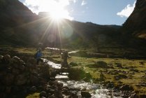 Junge Frau und Wanderführer überqueren Bach, Lares, Peru — Stockfoto