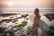 Donna che tiene la tavola da surf, cammina verso il mare, Balangan, Bali, Indonesia — Foto stock