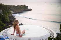 Woman sitting in spa pool, looking out to sea, Balangan, Bali, Indonesia — Stock Photo