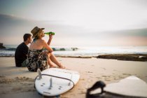 Casal sentado na praia com pranchas de surf, olhando para o mar, Nusa Lembongan, Indonésia — Fotografia de Stock