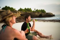 Paar sitzt am Strand und trinkt Bier, Nusa Lembongan, Indonesien — Stockfoto