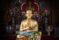 Golden buddha statue with flowers — Stock Photo