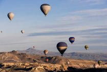 Hot air balloons floating over rock formations at sunrise in the sky — Stock Photo