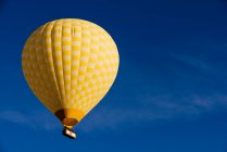 Globo amarillo de aire caliente flotando contra el cielo azul, Goreme Nationa - foto de stock
