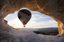 Balão de ar quente emoldurado entre a formação de rocha ao nascer do sol, Goreme — Fotografia de Stock
