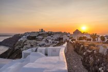Vista de paredes caiadas de branco e cidade ao pôr do sol, Oia, Santorini — Fotografia de Stock