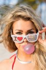 Portrait of young woman wearing sunglasses, blowing bubble gum, — Stock Photo