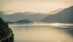 Salida del sol sobre las montañas brumosas, Lago de Como, Italia - foto de stock