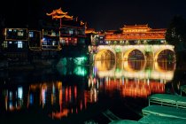 Мост через реку, освещенный ночью, Фэнхуан, Хунань, Китай — стоковое фото