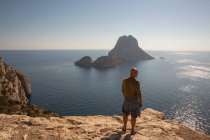 Mid adult male tourist looking out to Es Vedra from cliff, Ibiza — Stock Photo