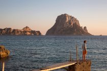 Jovem olhando para fora do cais velho ao pôr do sol, Ibiza, Espanha — Fotografia de Stock