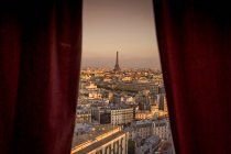 Red curtained window view of cityscape with distant Eiffel Tower — Stock Photo
