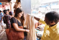 Junge Touristin betrachtet Textilien am Marktstand in Mumbai — Stockfoto