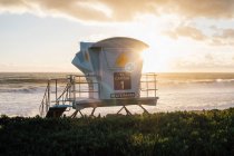 Lifeguard tower by ocean at sunset — Stock Photo