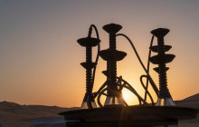 Арабські шифи (водяні труби) на столі в пустелі під час заходу сонця. — стокове фото