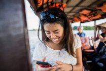 Mujer mirando la foto en el teléfono móvil en el barco de crucero, Mekong De - foto de stock