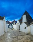 Allée pavée et maisons de trullo blanchies à la chaux au crépuscule, Alberobello, — Photo de stock