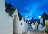 Allée pavée et maisons de trullo blanchies à la chaux au crépuscule, Alberobello, — Photo de stock