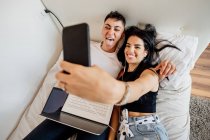 Jeune couple lesbienne allongé sur un lit, prendre selfie avec téléphone portable — Photo de stock
