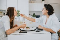 Two women with brown hair sitting at a table, eating sushi. — Stock Photo