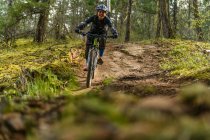 Woman mountain-biking in a forest in the Canadian mountains — Stock Photo