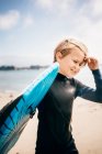 Retrato de un joven con traje de neopreno, llevando tabla de surf al océano, Santa Barbara, California, EE.UU.. - foto de stock