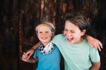 Portrait de deux garçons souriants, bras autour de l'épaule, regardant la caméra. — Photo de stock